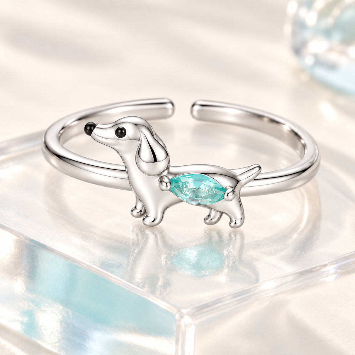 Close detail of the silver dachshund ring and aqua crystal on a clear display